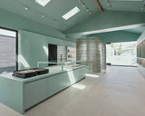 Modern kitchen with light green cabinets and a glass island.