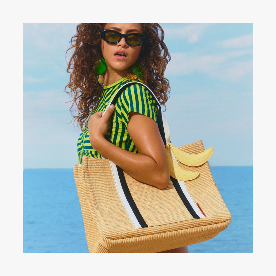 Natural | Woman standing by the ocean holding a Canopy Tote with the Banana Charm