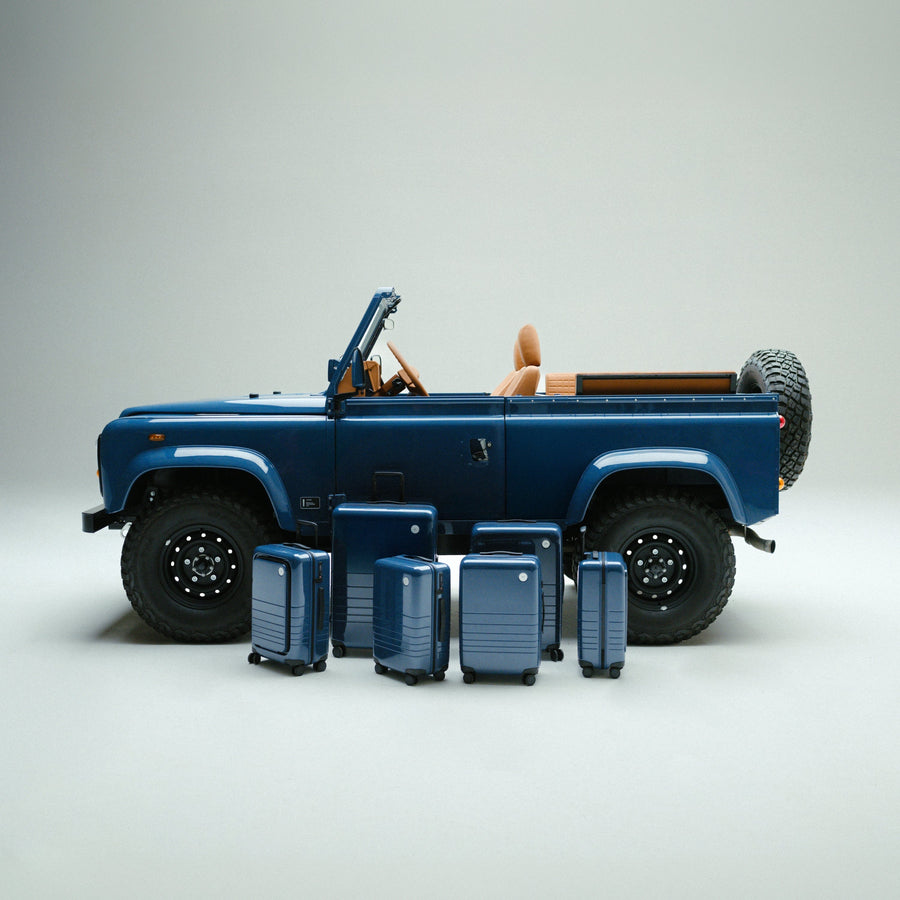 Arles Blue | Side view of Land Rover Defender in Arles Blue with suitcases in front