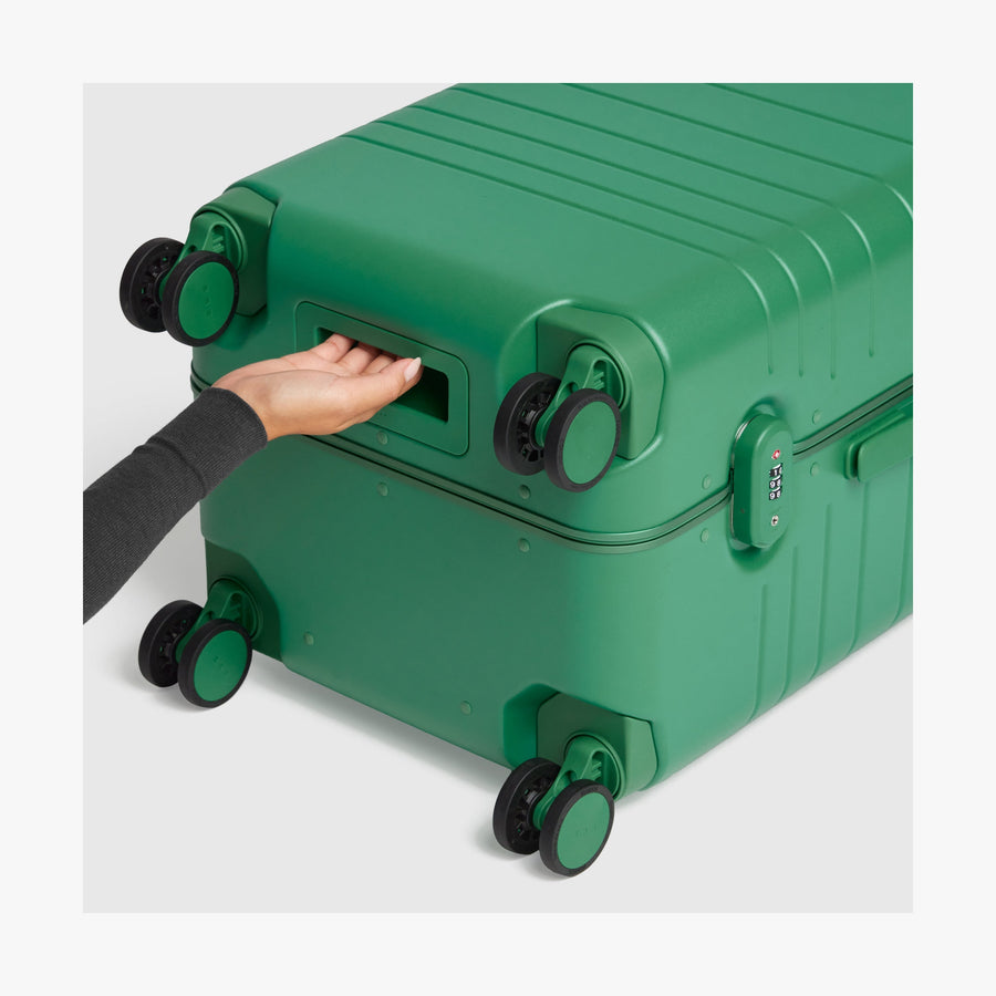 Jungle Green | Close-up view of a hand gripping the built-in underside handle of a Jungle Green Hybrid suitcase