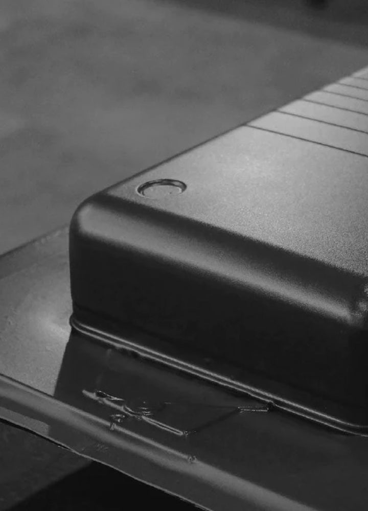 A close-up black and white photograph of one of our Monos Carry-On luggage pieces being manufactured.